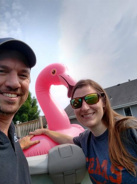 Adoption Profile Photo. Jessica and Nathan laugh. One hand each on an inflatable pool toy shaped like a flamingo.