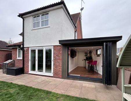 Back of a detached house and side garden room with open bifold doors