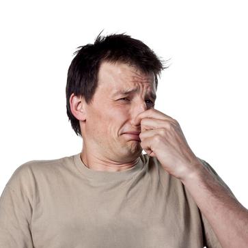 man pinching his nose because of an unbearable smell