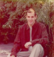 Outdoor picture of David, sitting, smiling looking at camera