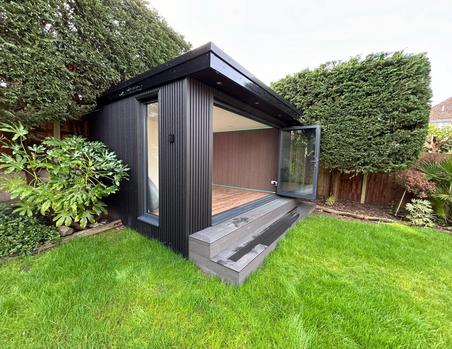 Garden room with black slatted cladding, 3 panel bifold doors and a full length side window