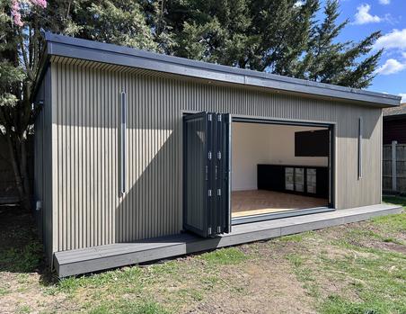 Garden room with beige slatted cladding and open 5 panel bifold doors showing a back bar and TV