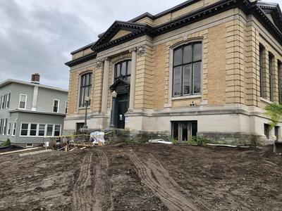 Front shot of library building with equipment tracks through dirt.