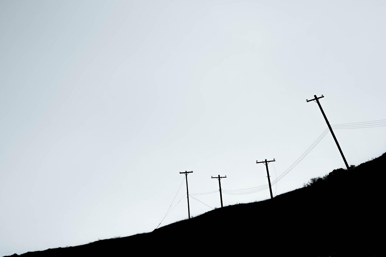 telephone poles over hill black and white