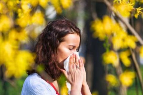 Woman blowing nose from allergies