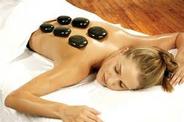 lady lying on table with towl on lower extremities with 6 hot stones on her back