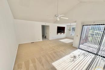 Interior of 755 21st Ave #755, SF showing a large open room with grey carpets, cream walls, and wood trim around windows, baseboards and the fireplace on the far side of the room.