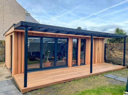 Modern cedar clad garden room with 3 panel bifold doors, full length windows, integral shed and black pergola in Dartford, Kent built by Robertson Garden Rooms