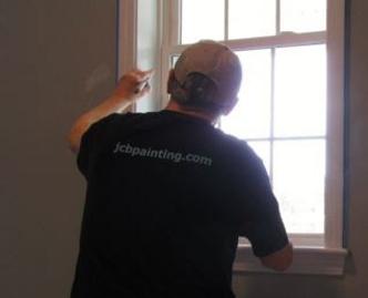 Owner/operator painting an interior window trim in Norton, MA.