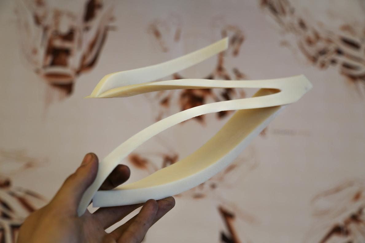 hand holding 3d printed part over blurry design background