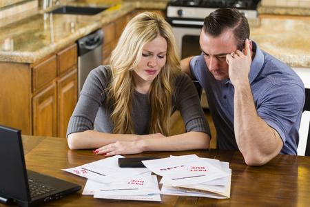 Married couple looking at paperwork and their laptop, stressed and upset