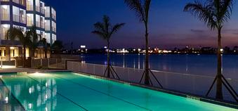 Hotel poolside at dusk with lights and palm trees