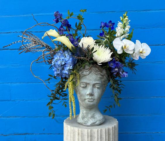 Bubble bowl with white hydrangea, three red roses, three green orchids, dusty miller, and filler.