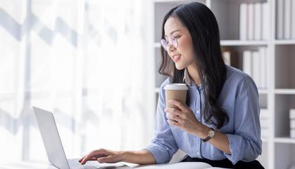 Young lady at a business office studying using a laptop.