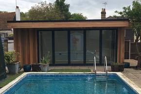 Modern cedar clad pool house garden room with bifold doors, changing area and shower in Feering, Braintree built by Robertson Garden Rooms