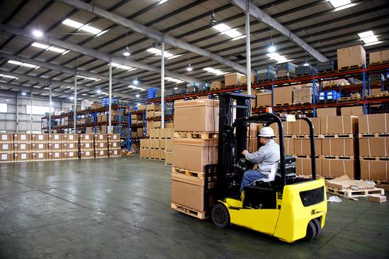 Forklift operator moving boxes in a warehouse, showcasing the dynamic work environment and opportunities at our company.