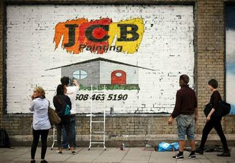 jcb painting logo on brick wall.