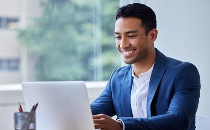 Image of a young business professional at an office working with a laptop