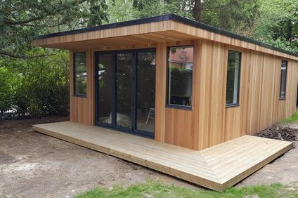 Modern cedar clad garden room with 2 windows either side of 3 panel bifold doors. Another 2 windows are on the side.