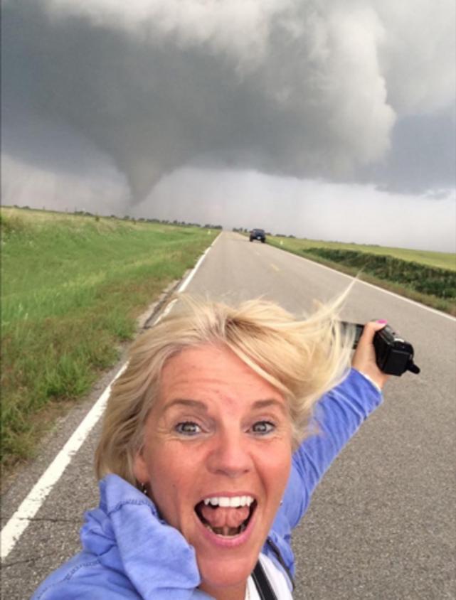 Smiling happy storm chasing tours guest filming tornado