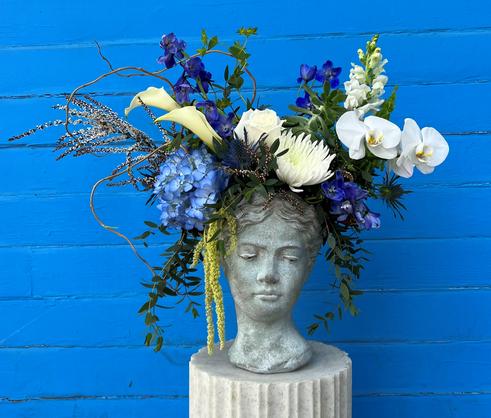 Bubble bowl with white hydrangea, three red roses, three green orchids, dusty miller, and filler.