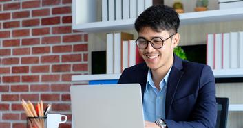 Male employee working happily with his laptop.