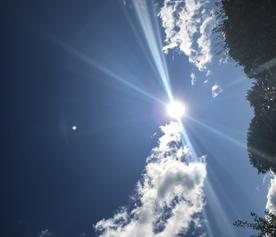 Bright sunlight streaming through fluffy clouds in a blue sky