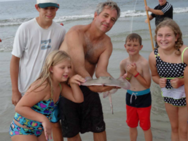 family holding stingray on the beach