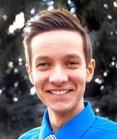 A head-shot of Trent, outdoors, smiling, looking at the camera