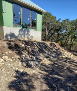 A landscaping job by wilson landscape in San Antonio texas of a circular rumblestone paver patio design with a beautiful stone fire pit in the middle and outdoor seating with river rock bordering