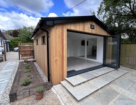 Garden pilates studio with red cedar cladding and open 3 panel bifold doors