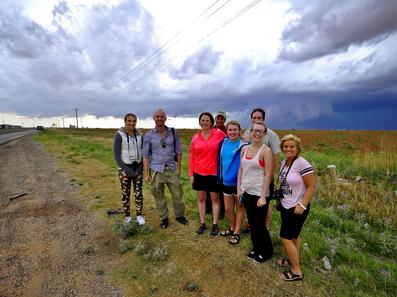 Tour guests smiling in front of tornado warned cell