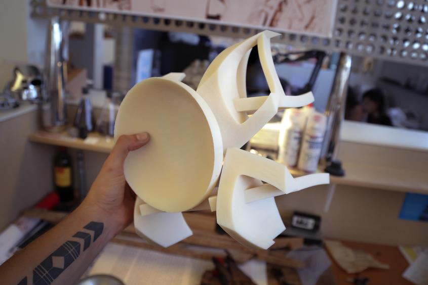 hand holding 3d printed motorcycle fairings over blurry studio background
