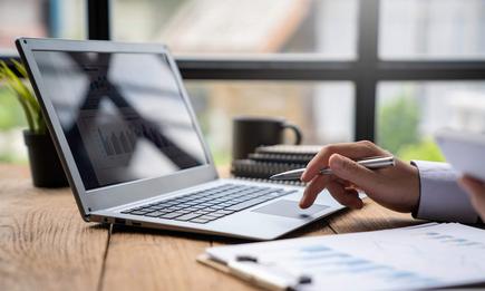 man holding a cellphone and looking at a laptop