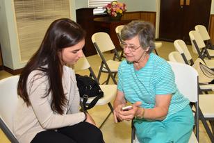 Photo of a FriendShip volunteer helping a member learn to use her cell phone.