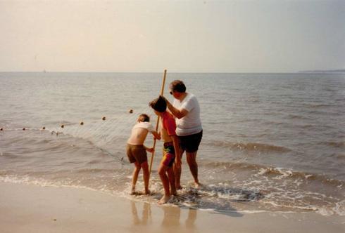 father and children hauling in a seine net full of fish