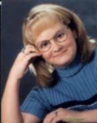 Senior picture of Jennifer, with head leaning on right hand with right elbow on table, smiling, looking at camera.