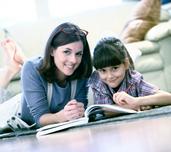 Image of a mother and daughter lying on the floor reading a book together