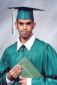 Binyam, in high-school cap and gown, holding diploma, even expression looking at camera.