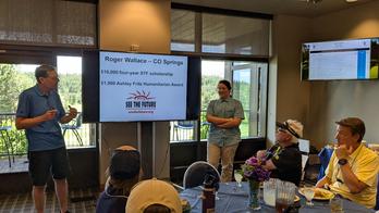 Tom Theune & Roger Wallace standing in front of the golfers at the 19th hole lunch.