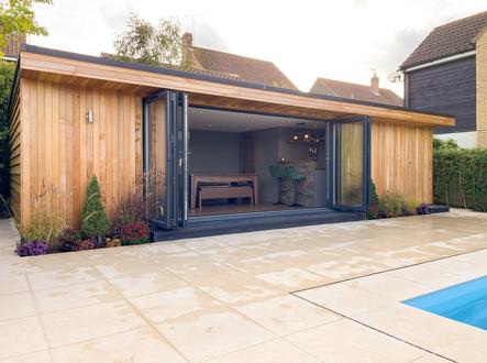 Modern cedar clad garden room with open bifold doors showing a bar and pool table