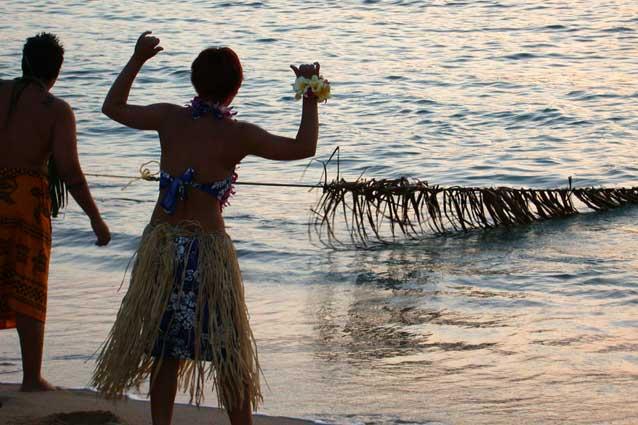 Hawaii men pulling in a seine net made of leaves and tree limbs