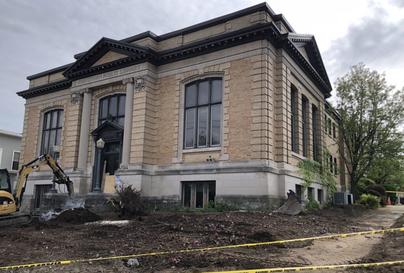 Library building with cleared out lawn and excavator equipment