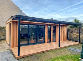 Modern cedar clad garden room with 3 panel bifold doors and black pergola in Dartford, Kent built by Robertson Garden Rooms