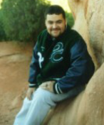 Outdoor picture of Solomon, leaning on a rock, smiling at camera.