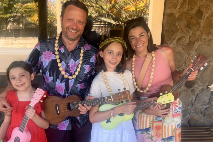 Nicholas, Chelsey, Emma, and Maddie Murdock holding ukuleles together during a family trip to Hawaii.
