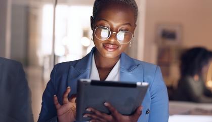 Young business woman standing up looking on a tablet.