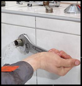 Using a wrench to turn off water supply.