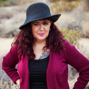 Author photo. Red sweater. Black shirt. Hat. Shoulder-length hair.
