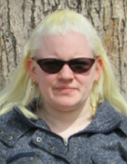 Outdoor picture of Susie, wearing sunglasses and looking at the camera